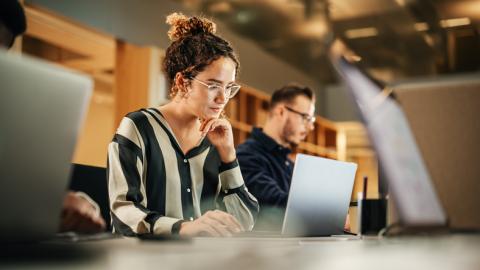 A young woman works intently on a laptop