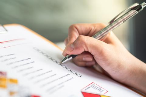 A hand ticks off boxes on a paper form