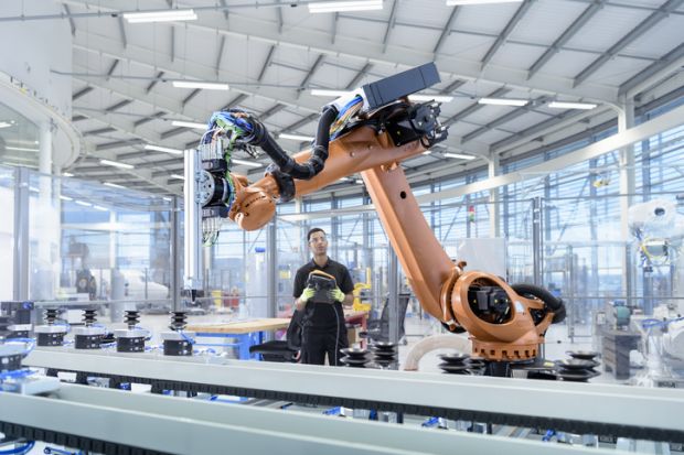 An engineer programmes a robot in a robotics research facility, illustrating regional growth
